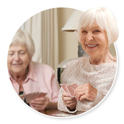 Senior woman smiling while playing cards with a friend
